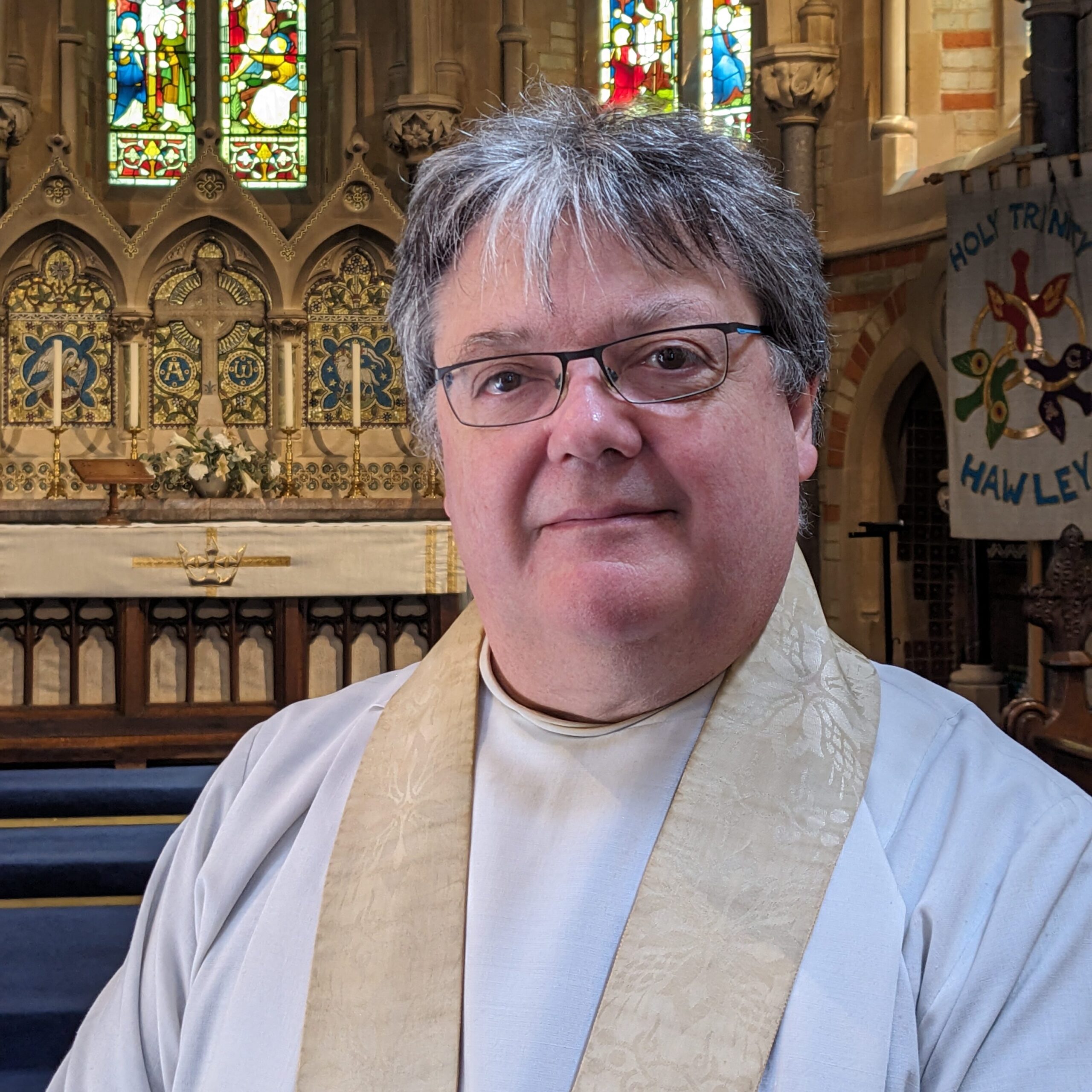 A photograph of the Rev’d Canon William Perry, SSC, pictured in front of the altar at Holy Trinity church, Hawley.